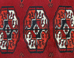 A vintage Pakistani Princess Bokhara rug featuring repeating geometric motifs in red, black, and white.