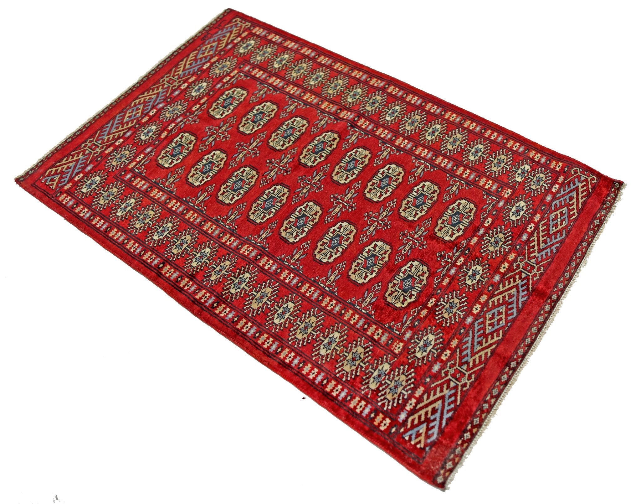 A vintage Pakistani Princess Bokhara rug featuring a repeating geometric pattern on a red field.