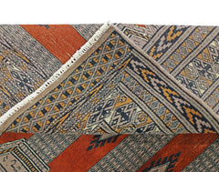 A vintage Pakistani Princess Bokhara rug featuring a geometric pattern in rust, black, and tan.
