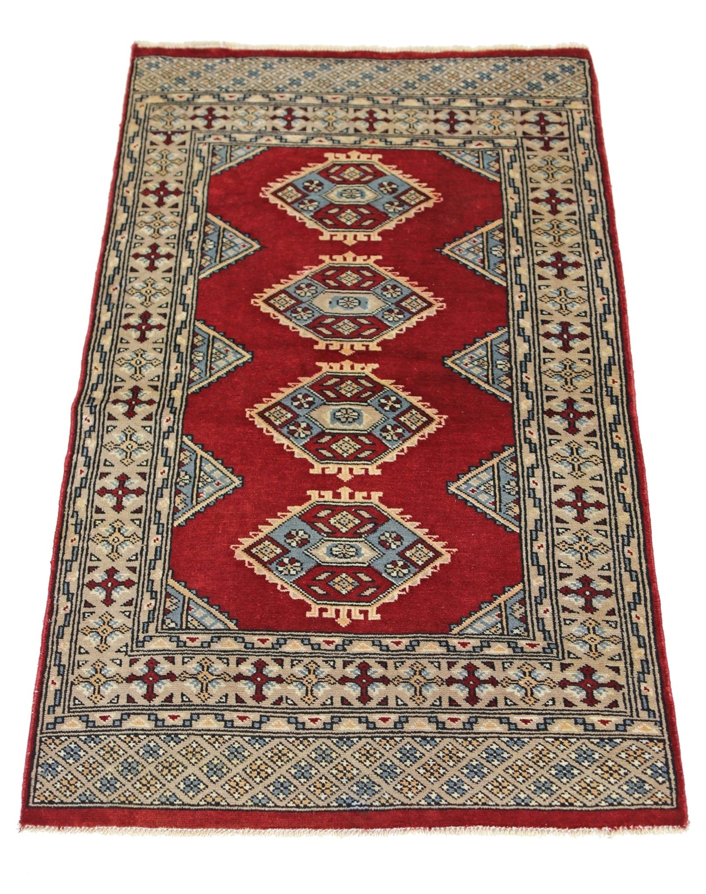 A vintage Pakistani Princess Bokhara rug featuring four geometric medallions on a red field.