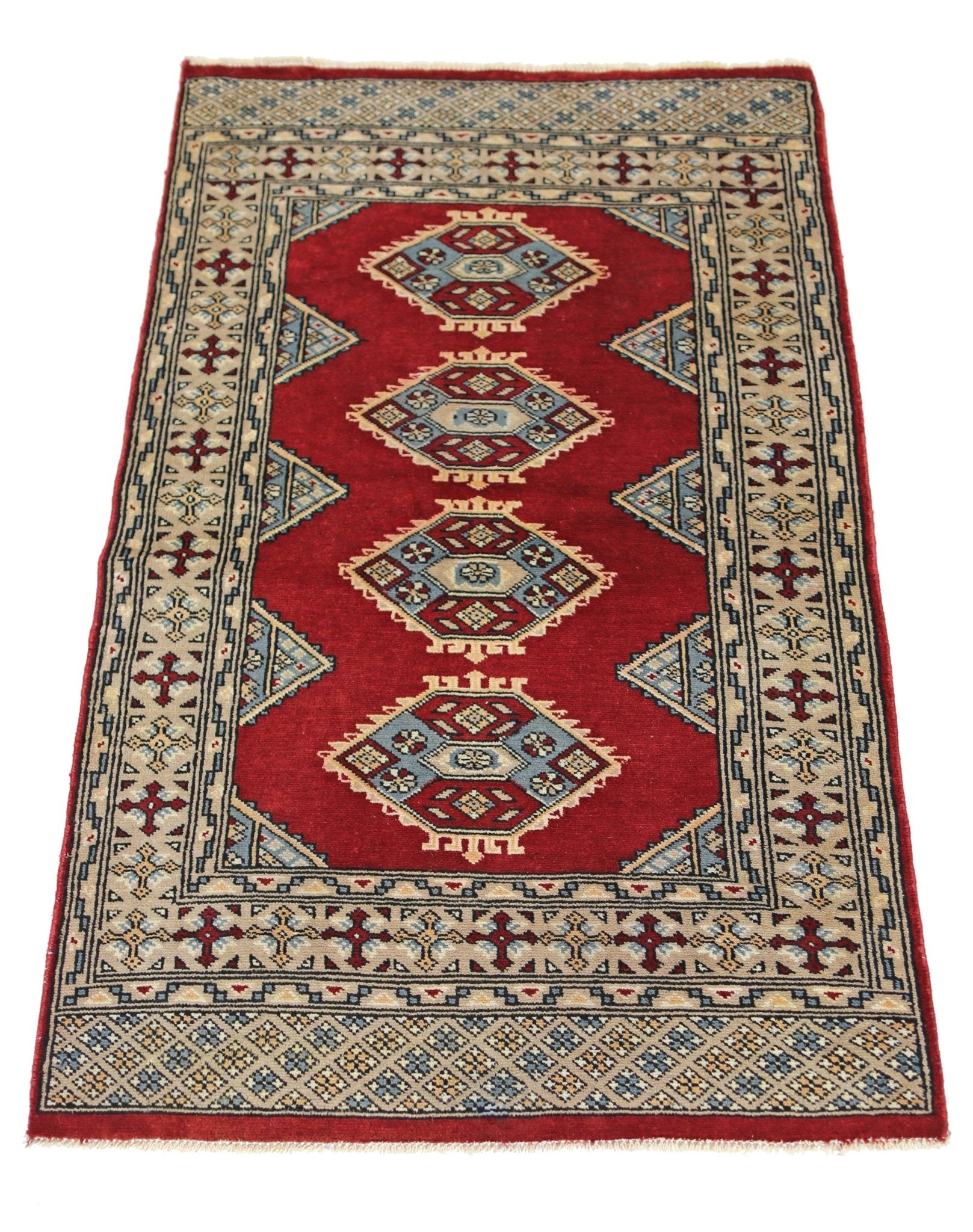 A vintage Pakistani Princess Bokhara rug featuring four geometric medallions on a red field.