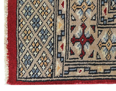 A vintage Pakistani Princess Bokhara rug featuring a geometric pattern in red, beige, and blue.