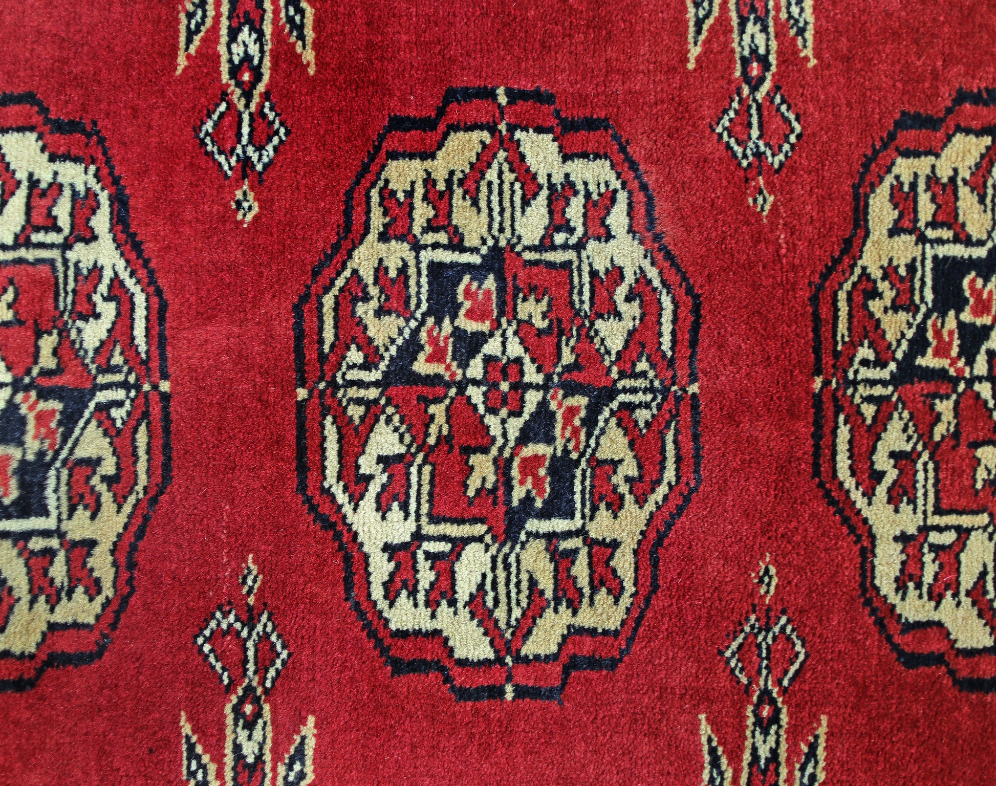 A vintage Pakistani Princess Bokhara rug featuring a repeating geometric pattern in red, cream, and black.