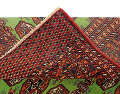 A vintage Pakistani Princess Bokhara rug featuring a green field with red geometric patterns.