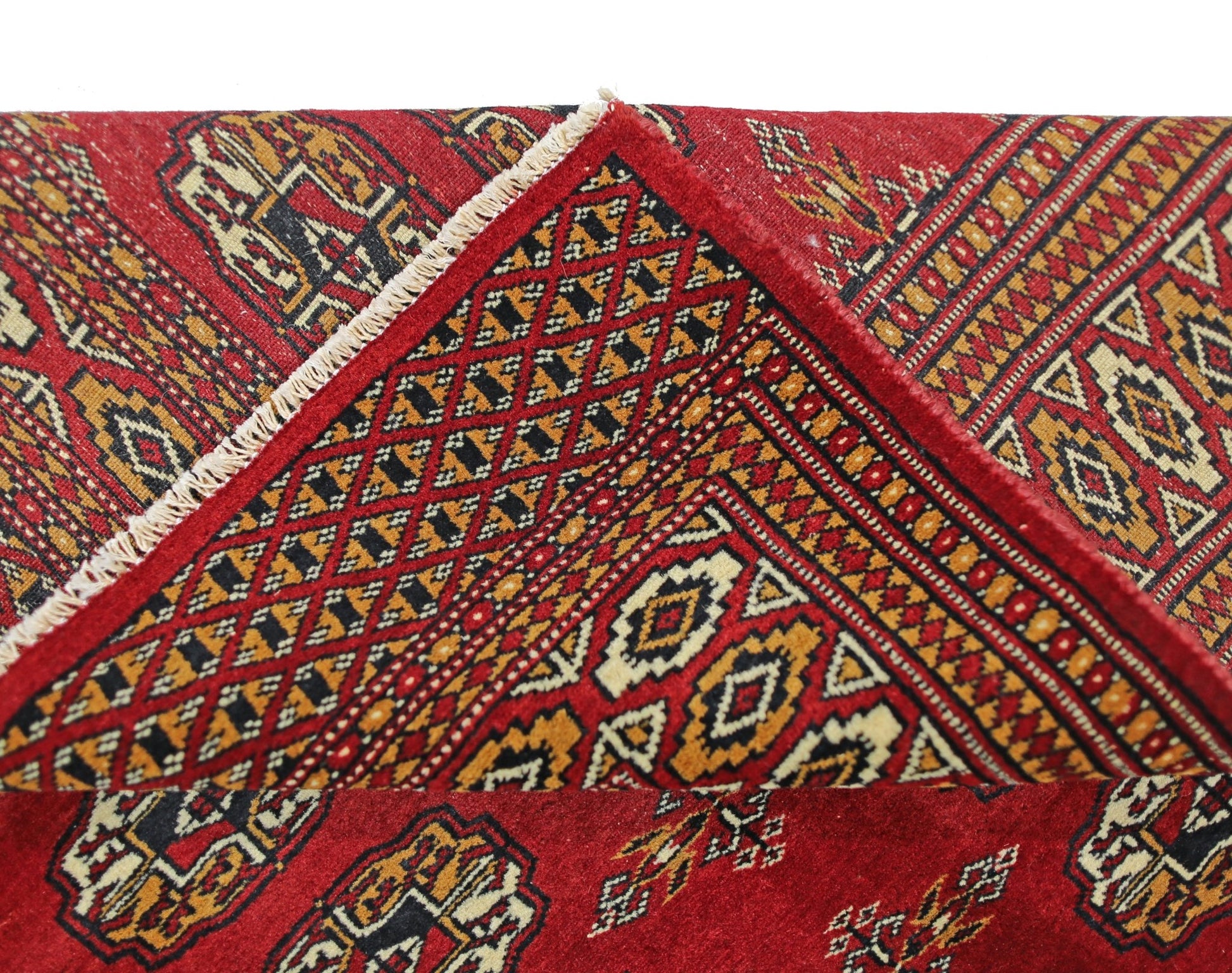 A vintage Pakistani Princess Bokhara rug featuring a red field with geometric patterns and a folded corner.