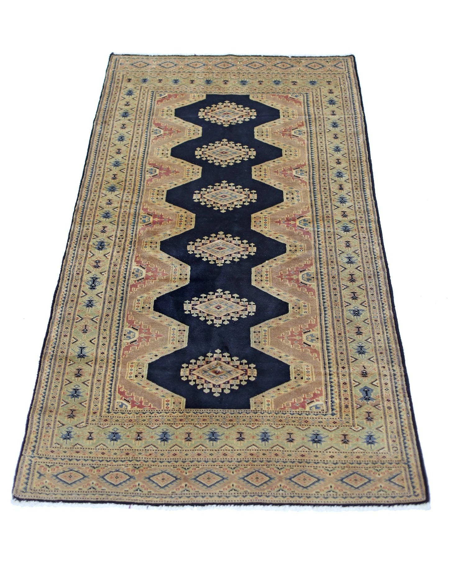 A vintage Pakistani Princess Bokhara rug featuring a dark blue central medallion on a tan field.