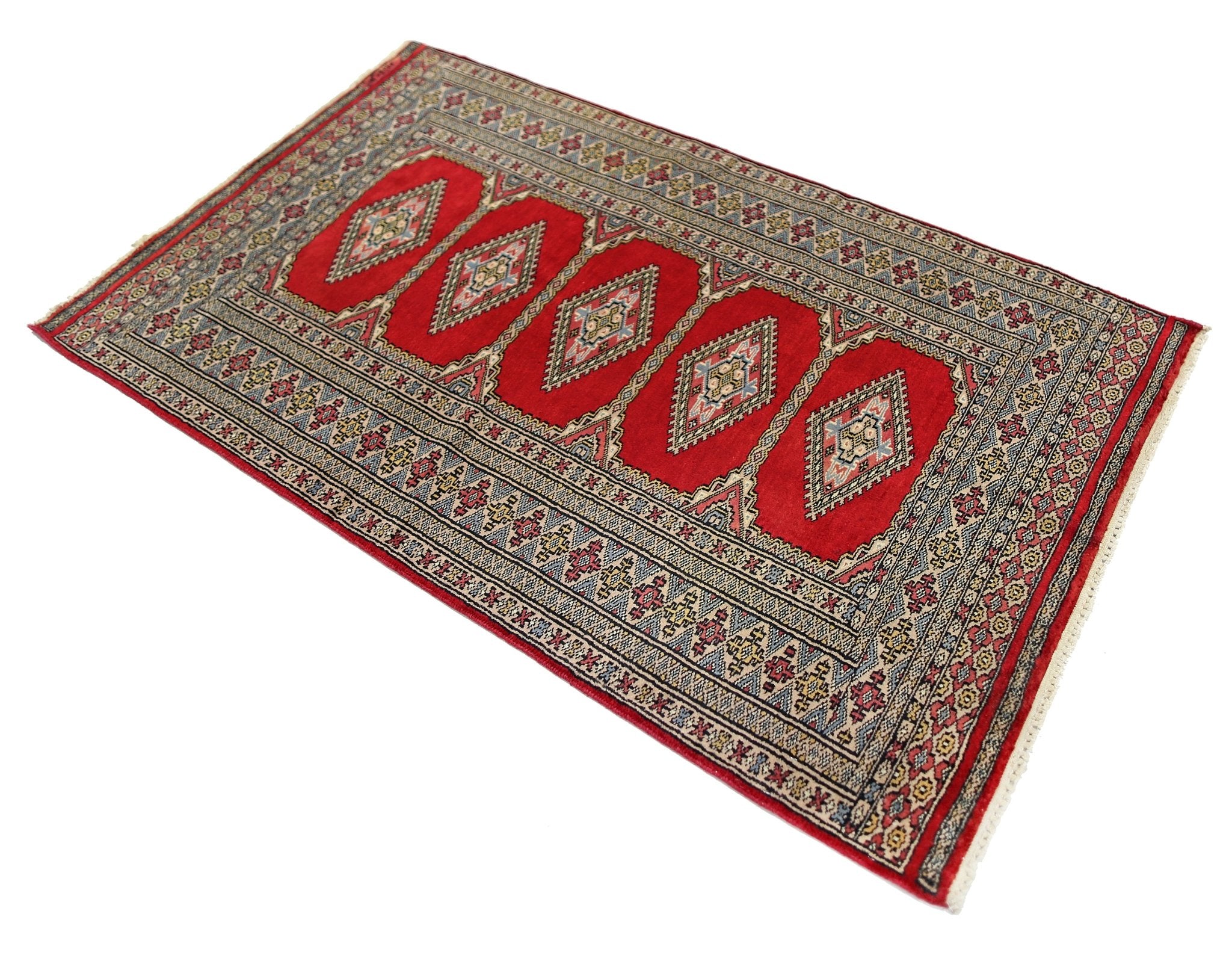 A vintage Pakistani Princess Bokhara rug featuring five red diamond medallions on a wool pile.