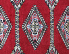 A vintage Pakistani Princess Bokhara rug featuring a repeating diamond pattern in red, blue, and cream.