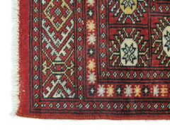 A vintage Pakistani Princess Bokhara rug featuring a geometric red pattern and white fringe.