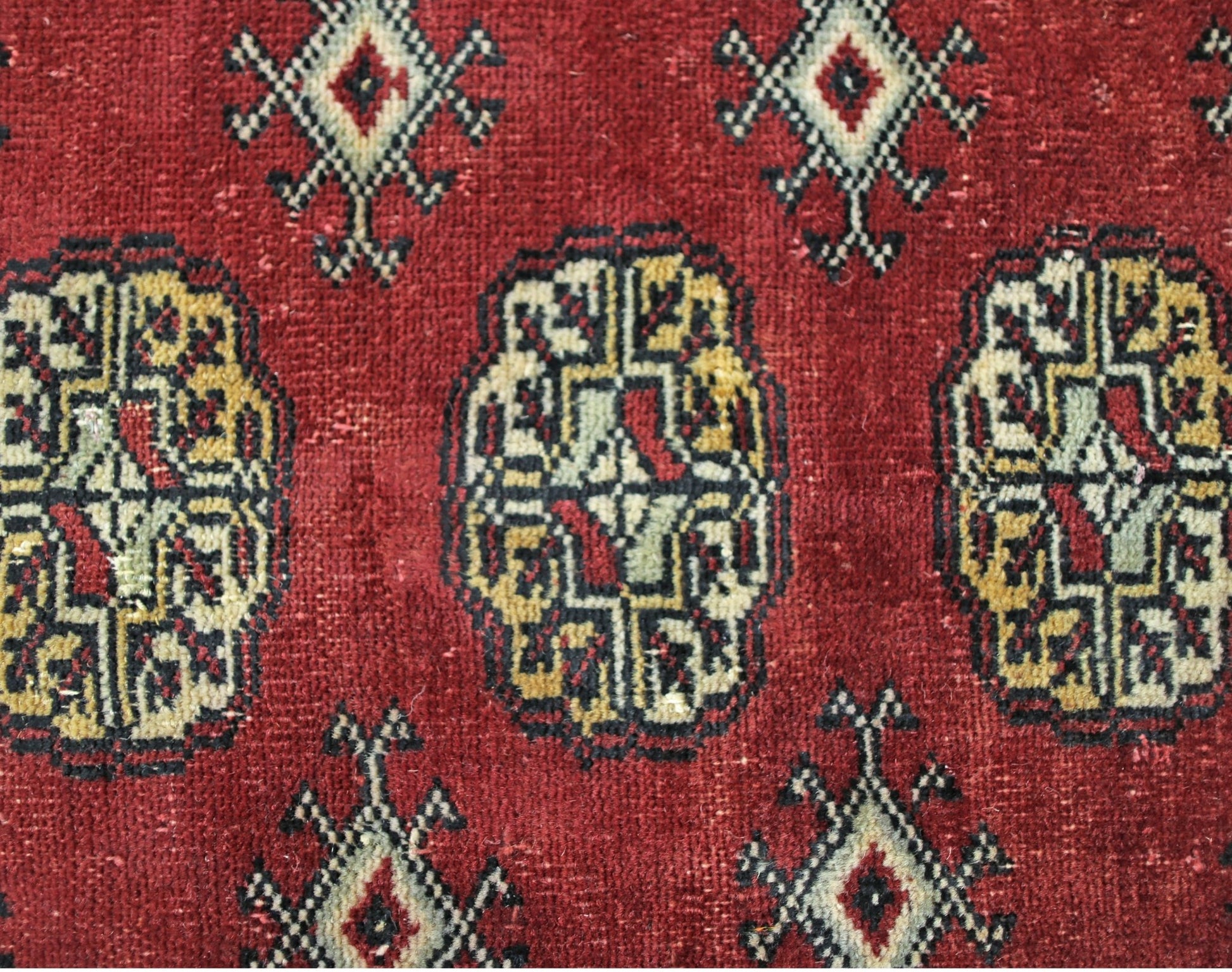 A vintage Pakistani Princess Bokhara rug featuring a deep red field with repeating geometric motifs.