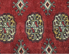 A vintage Pakistani Princess Bokhara rug featuring a deep red field with repeating geometric motifs.