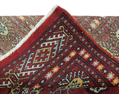 A vintage Pakistani Princess Bokhara rug featuring a geometric red pattern and white fringe.