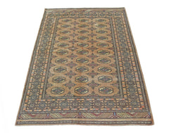 A vintage Pakistani Princess Bokhara rug featuring a repeating geometric pattern on a tan field.