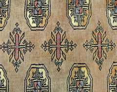 A vintage Pakistani Princess Bokhara rug featuring a repeating geometric pattern on a tan background.