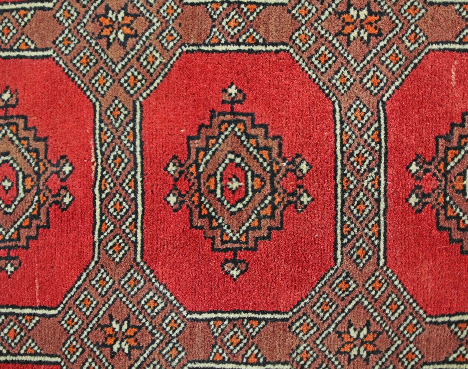 A vintage Pakistani Princess Bokhara rug featuring a geometric pattern in red and brown tones.