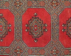 A vintage Pakistani Princess Bokhara rug featuring a geometric pattern in red and brown tones.