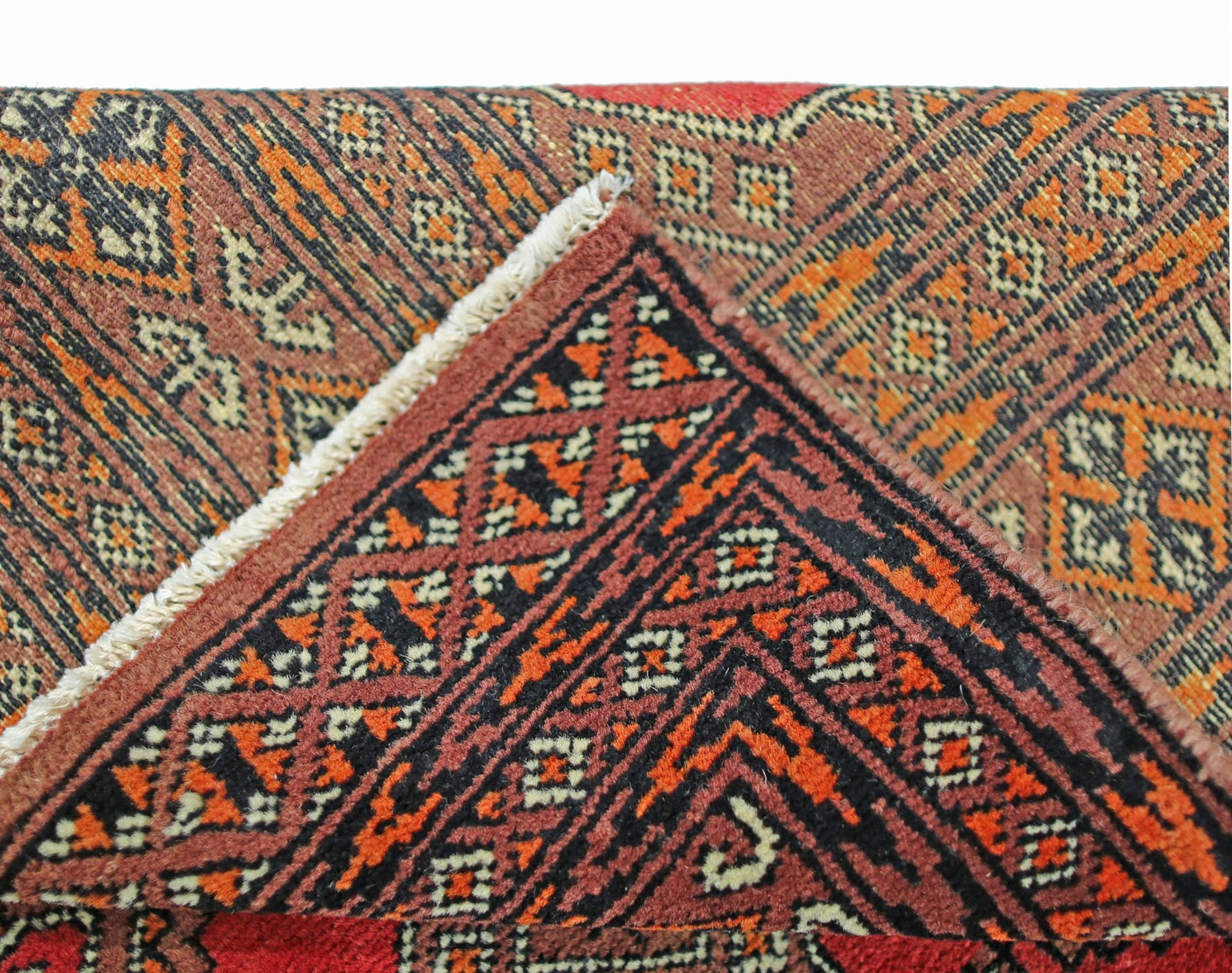 A folded vintage Pakistani Princess Bokhara rug featuring a geometric pattern in red and orange.