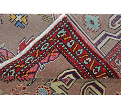 A vintage Pakistani Princess Bokhara rug with a folded corner showing its red and brown pattern.