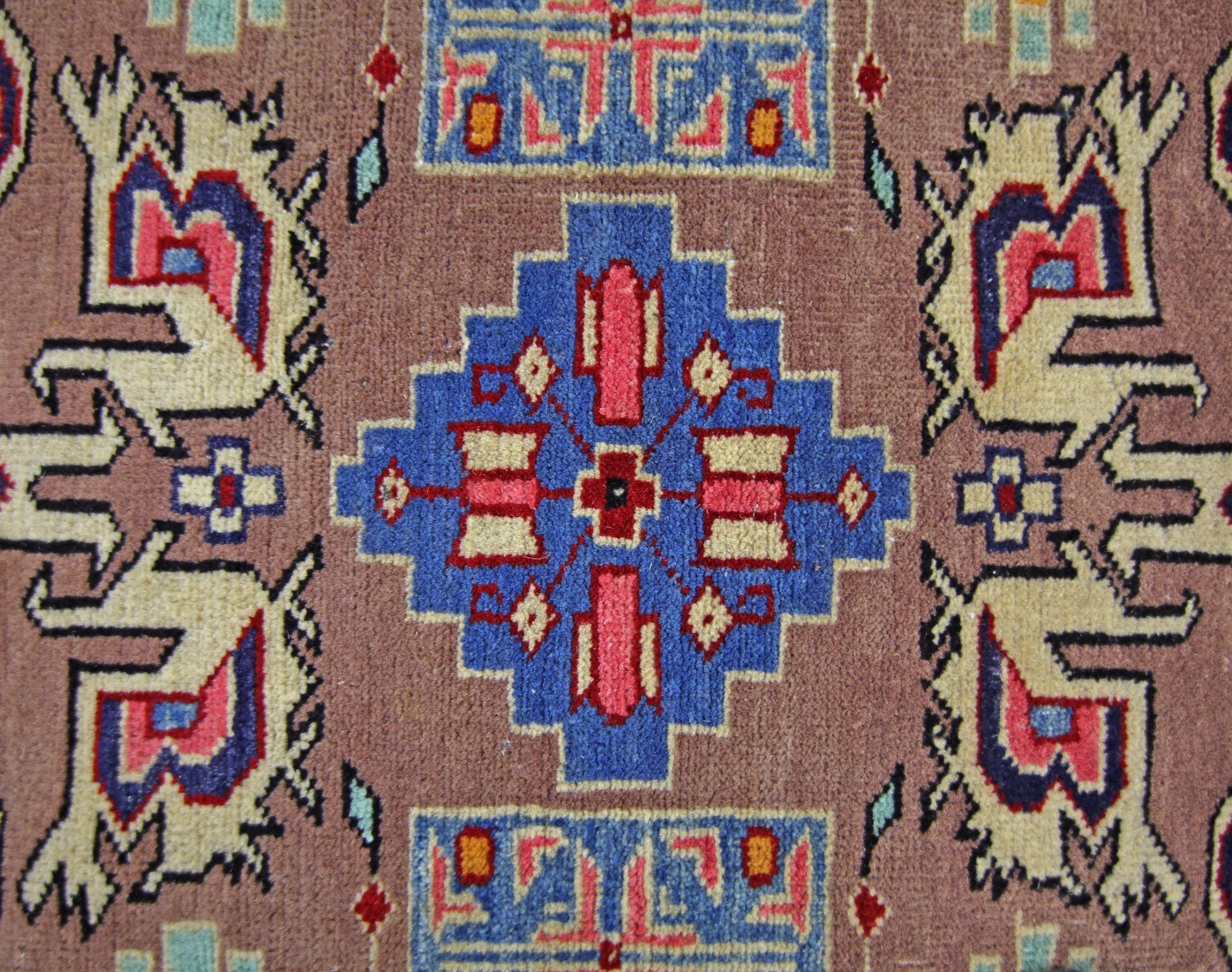 A vintage Pakistani Princess Bokhara rug featuring a geometric blue medallion on a brown field.