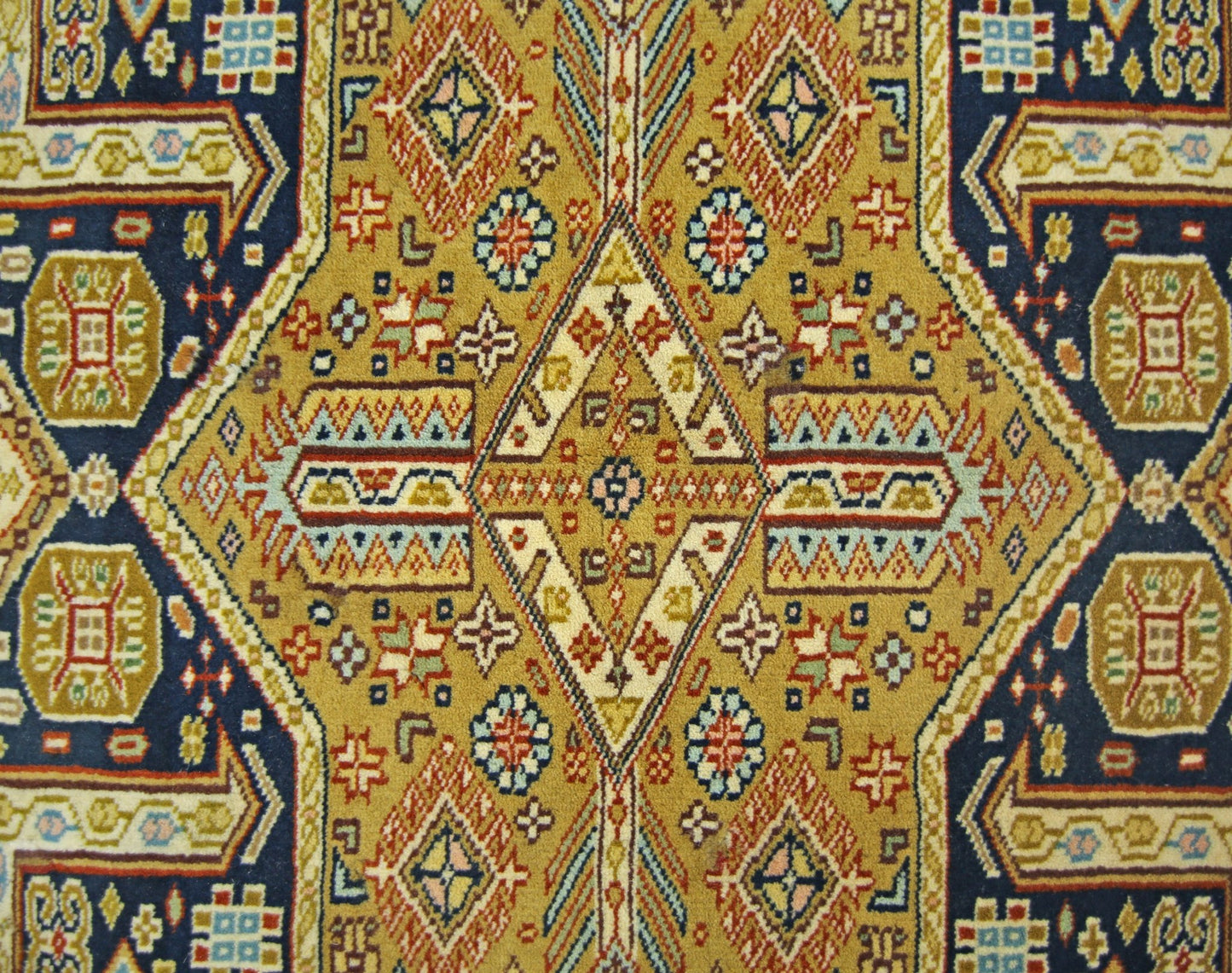 A vintage Pakistani Princess Bokhara rug featuring a geometric diamond pattern in gold and blue.