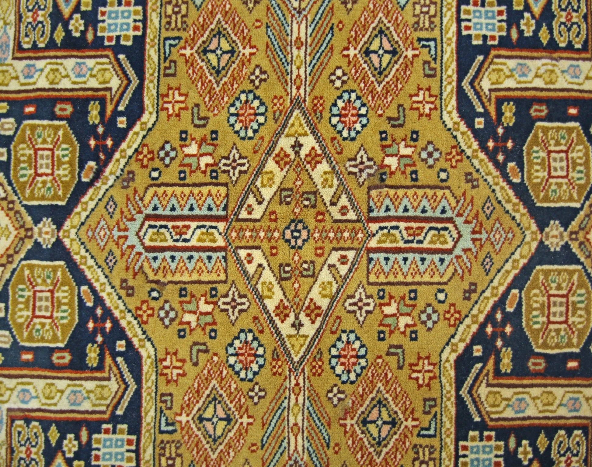 A vintage Pakistani Princess Bokhara rug featuring a geometric diamond pattern in gold and blue.