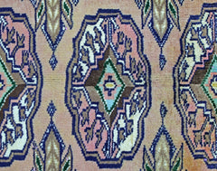 A vintage Pakistani Princess Bokhara rug featuring a repeating geometric medallion pattern in pink and blue.