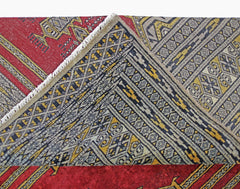 A vintage Pakistani Princess Bokhara rug with a folded corner showing its intricate geometric design.