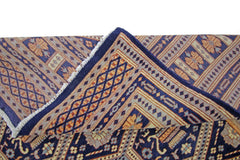 A vintage Pakistani Princess Bokhara rug with a folded corner showing its intricate geometric pattern.