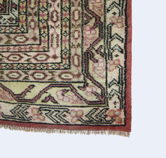 A vintage Pakistani Princess Bokhara rug featuring intricate geometric patterns in pink and cream.