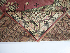 A vintage Pakistani Princess Bokhara rug with a folded corner revealing its intricate wool pattern.