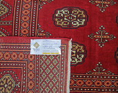 A vintage Pakistani Princess Bokhara rug featuring a deep red field with repeating geometric motifs.