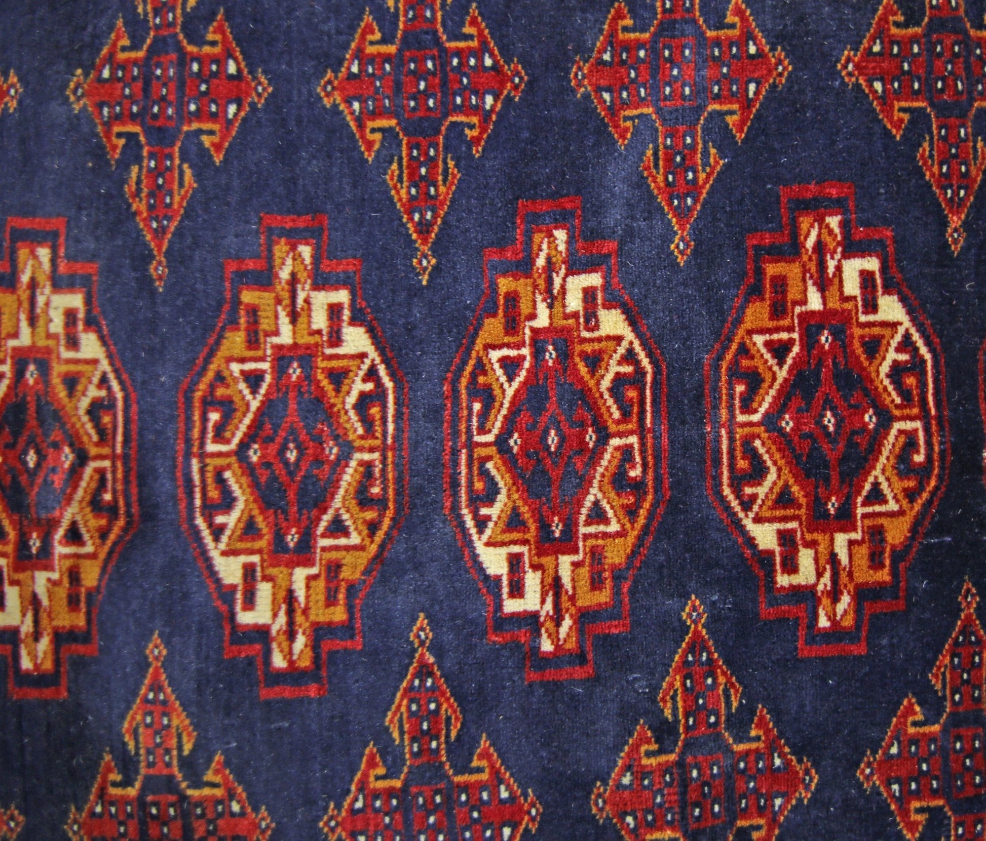 A vintage Pakistani Princess Bokhara rug featuring a repeating geometric pattern on a blue field.