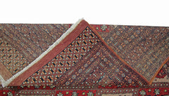 A vintage Pakistani Princess Bokhara rug with a folded corner showing its intricate geometric pattern.