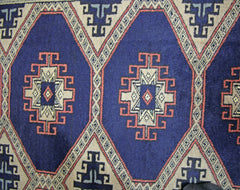 A vintage Pakistani Princess Bokhara rug featuring a repeating geometric diamond pattern in blue.