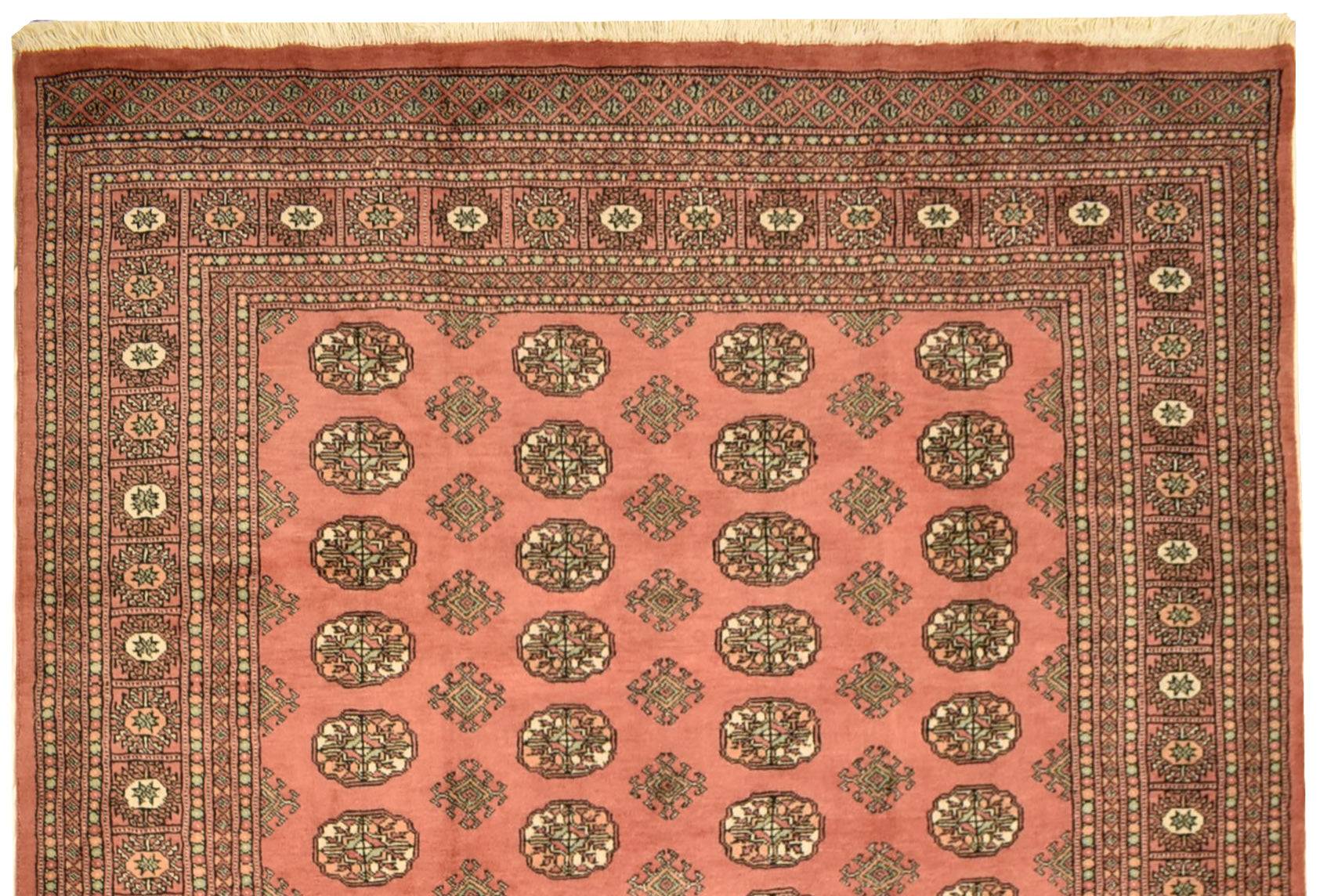 A handmade vintage Princess Bokhara rug featuring a repeating geometric pattern on a salmon field.