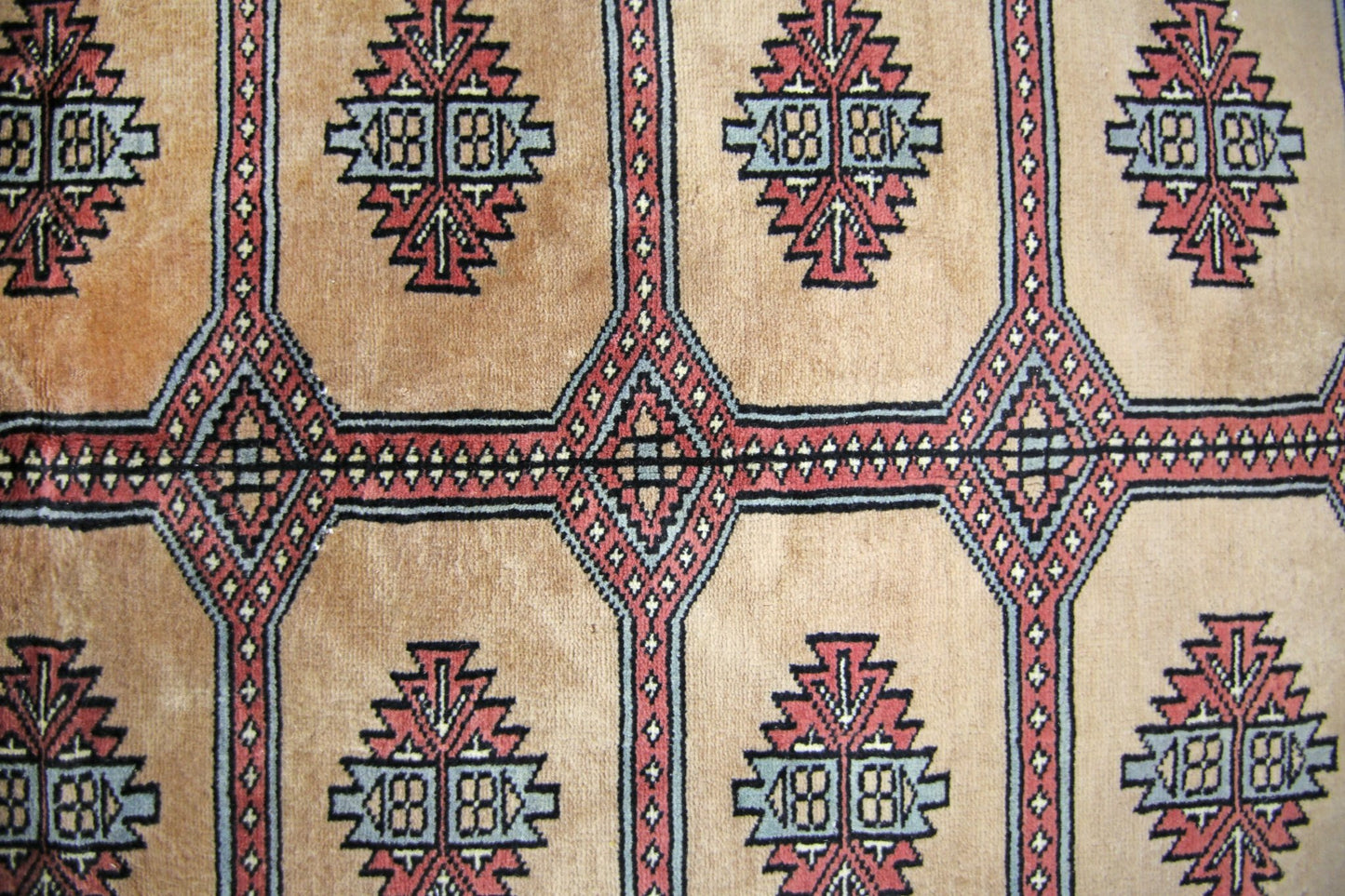 A vintage Pakistani Princess Bokhara rug featuring a geometric pattern in red, blue, and tan.