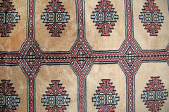 A vintage Pakistani Princess Bokhara rug featuring a geometric pattern in red, blue, and tan.