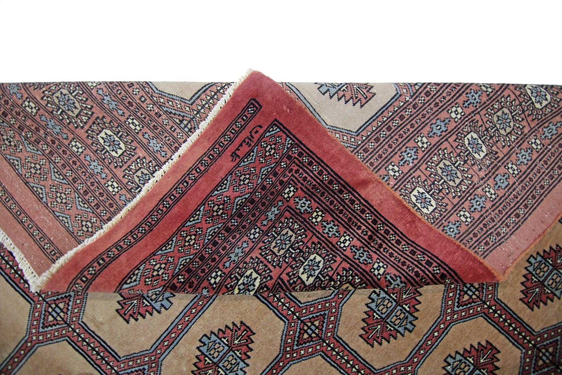 A vintage Pakistani Princess Bokhara rug with a folded corner revealing its intricate red pattern.