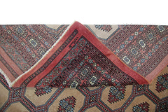 A vintage Pakistani Princess Bokhara rug with a folded corner revealing its intricate red pattern.
