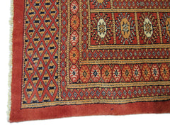A vintage Pakistani Princess Bokhara rug featuring a geometric diamond pattern in red and cream.