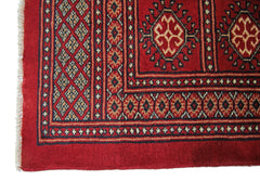 A vintage Pakistani Princess Bokhara rug featuring a geometric red pattern and fringed edges.