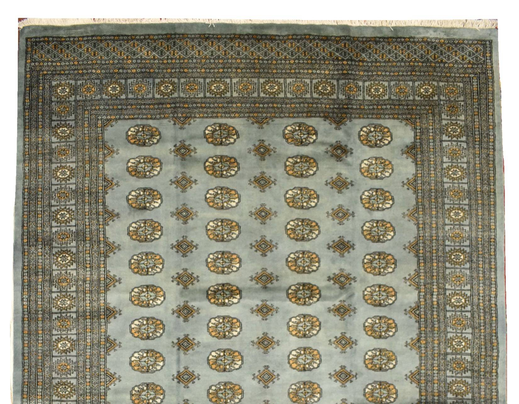 A handmade wool Princess Bokhara rug featuring a repeating geometric pattern on a light blue field.