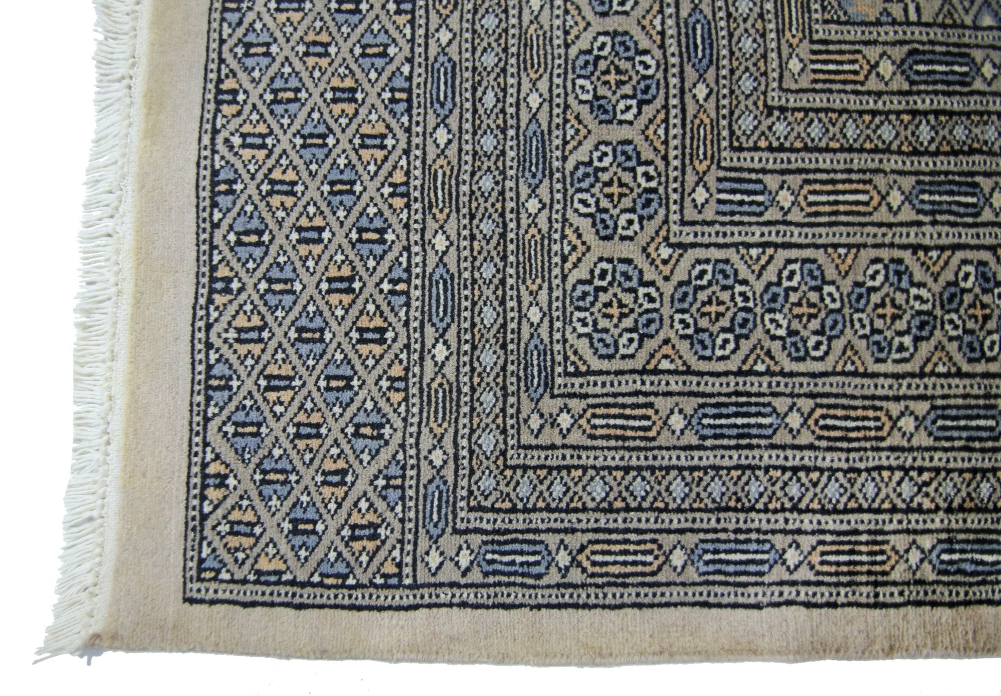 A vintage Pakistani Princess Bokhara rug featuring a geometric diamond pattern in blue and tan.