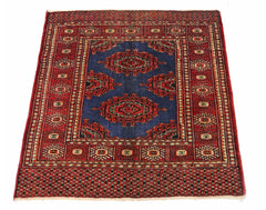 A vintage Pakistani Princess Bokhara rug featuring a blue field with red geometric medallions.