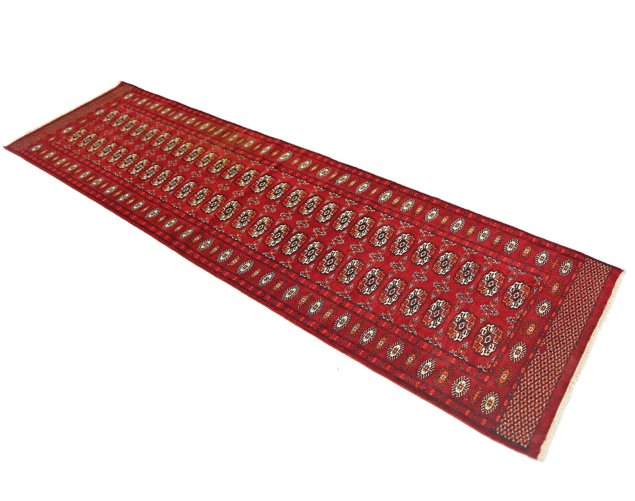 A vintage Pakistani Princess Bokhara runner rug featuring a repeating geometric pattern in red.
