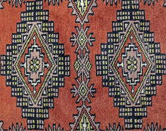 A vintage Pakistani runner featuring repeating geometric diamond motifs in red, black, and yellow.