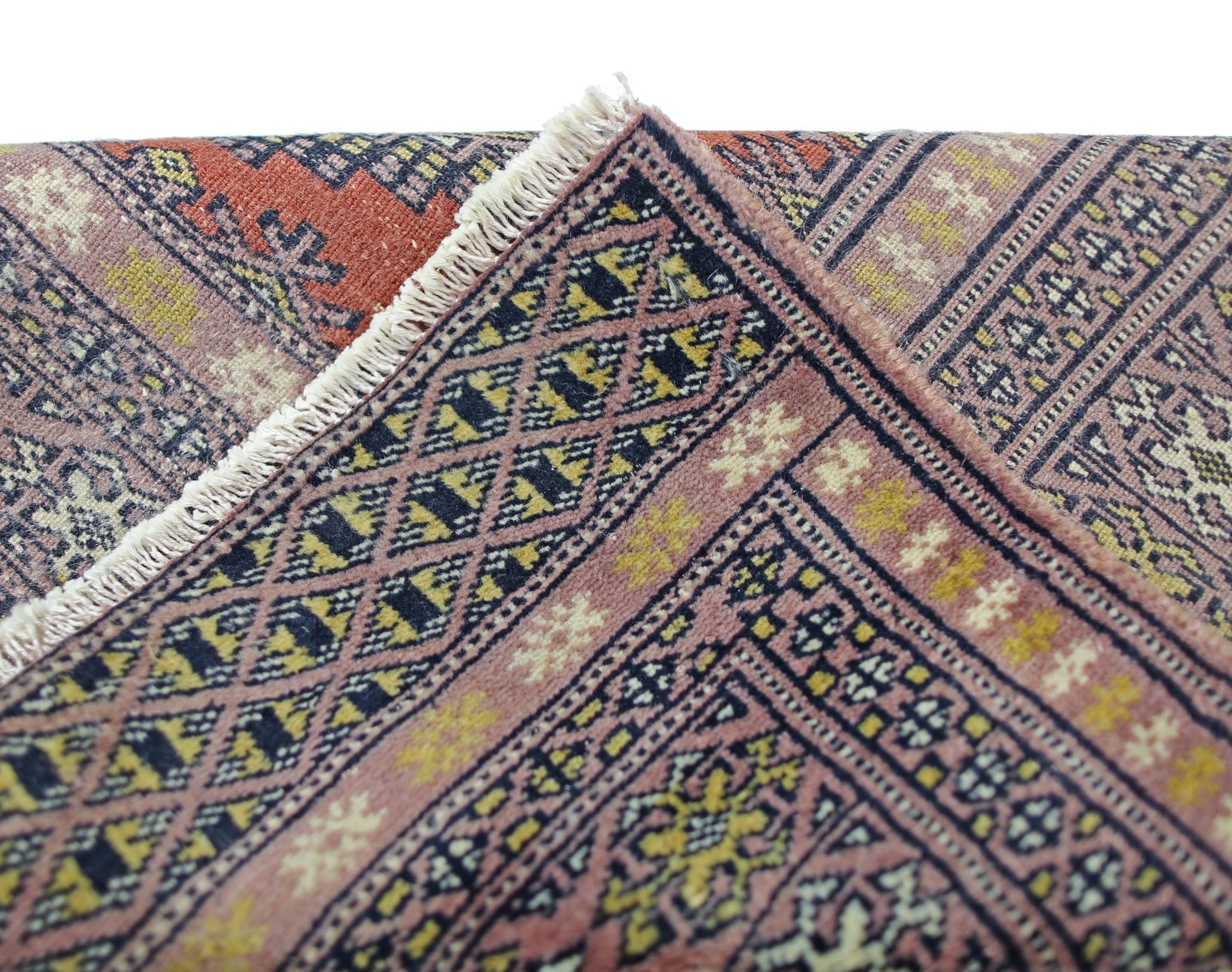 A vintage Pakistani Princess Bokhara runner featuring a geometric diamond pattern in pink and gold.