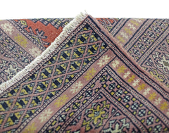 A vintage Pakistani Princess Bokhara runner featuring a geometric diamond pattern in pink and gold.