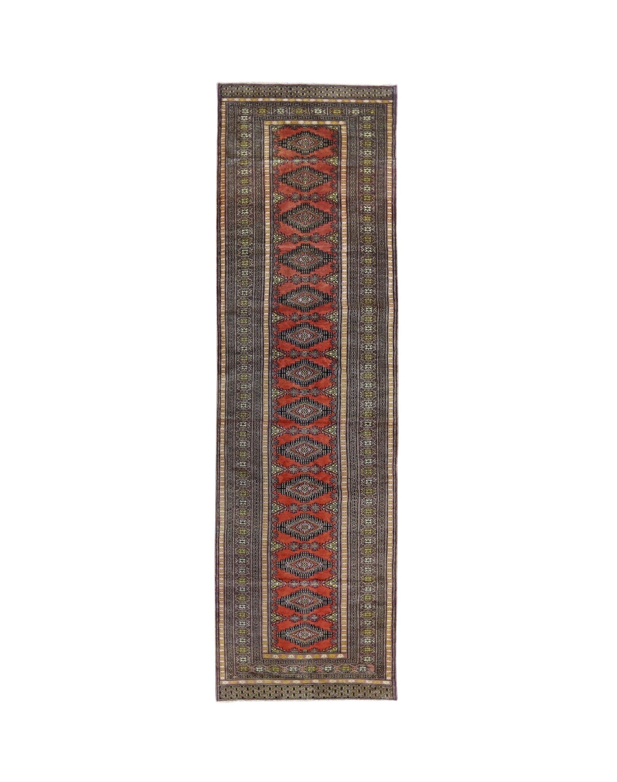 A vintage Pakistani runner rug featuring a repeating geometric pattern in red and dark tones.