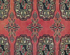 A vintage Pakistani runner featuring a repeating geometric pattern in red, black, and cream.
